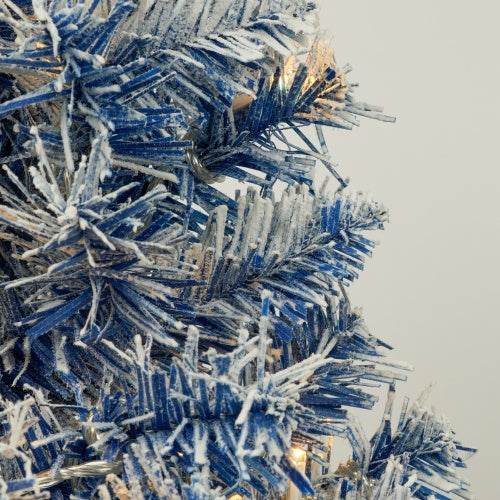 Close-up of blue pre-lit artificial Christmas tree branches with snow effect and LED lights