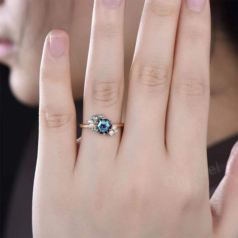 Gold prismatic brilliance six-claw zircon ring with geometric blue stone on woman's finger
