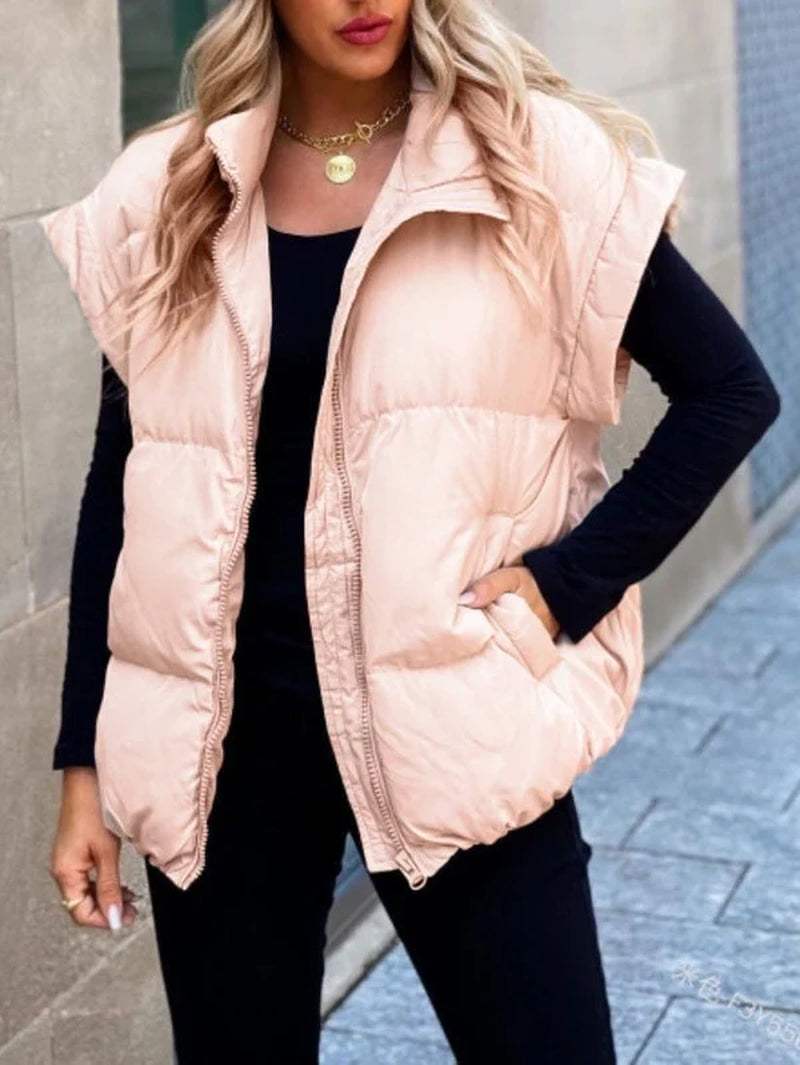 Stylish puffer vest in light pink, featuring a zip front and side pockets, perfect for layering in cooler weather.