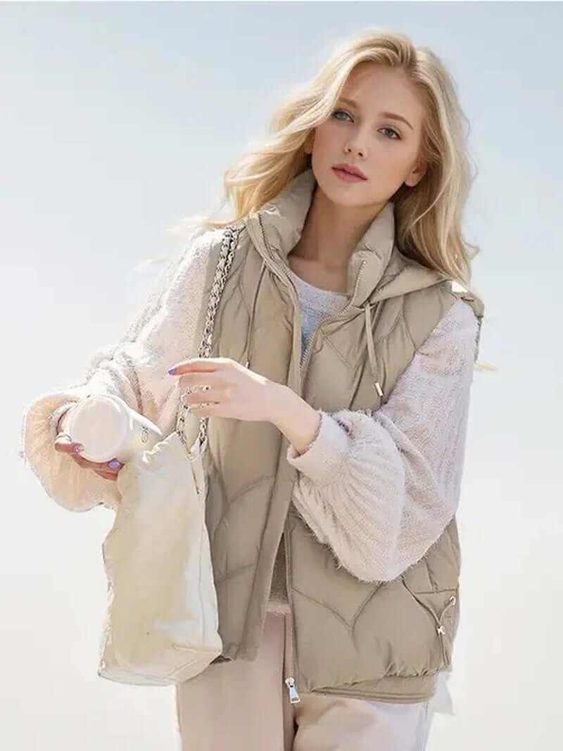 Stylish puffer vest with hoodie in beige, perfect for layering and casual outings, model holding a bag.