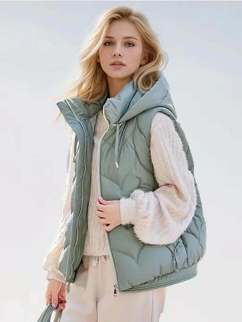 Stylish puffer vest with hoodie in soft green color, perfect for layered winter outfits.