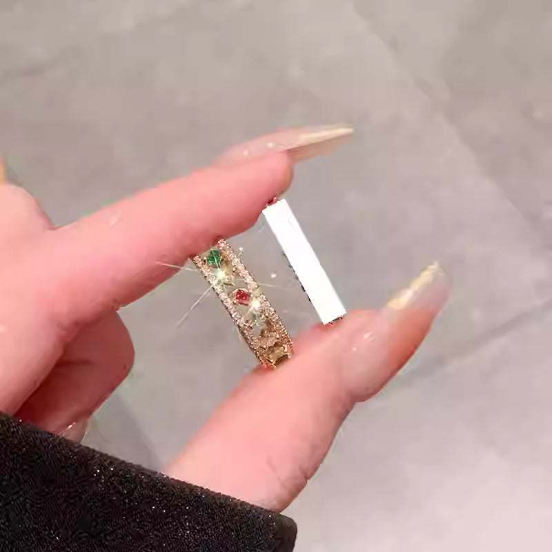 Close-up of a hand holding an adjustable rainbow gemstone ring with colorful zircon stones and a hollow out design