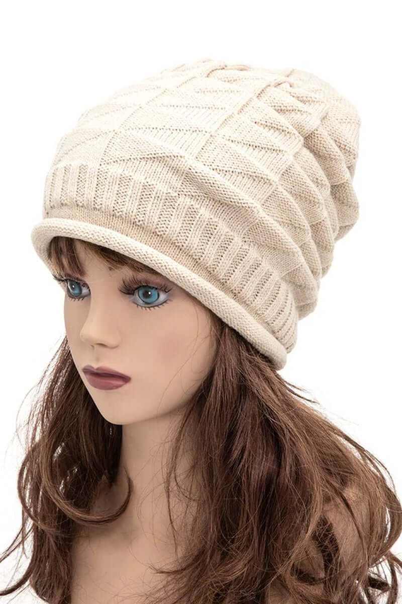 Ribbed slouchy unisex raised knit beanie in cream worn by mannequin with long hair.