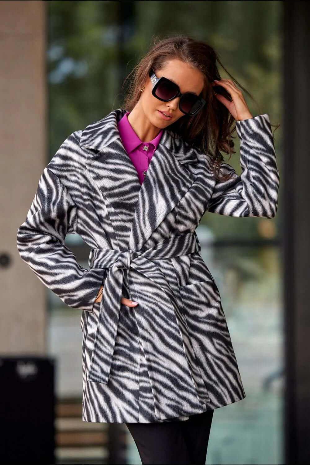Woman wearing Roco Fashion Longline Elegant Coat in zebra print with a belt and sunglasses, showcasing fall fashion.
