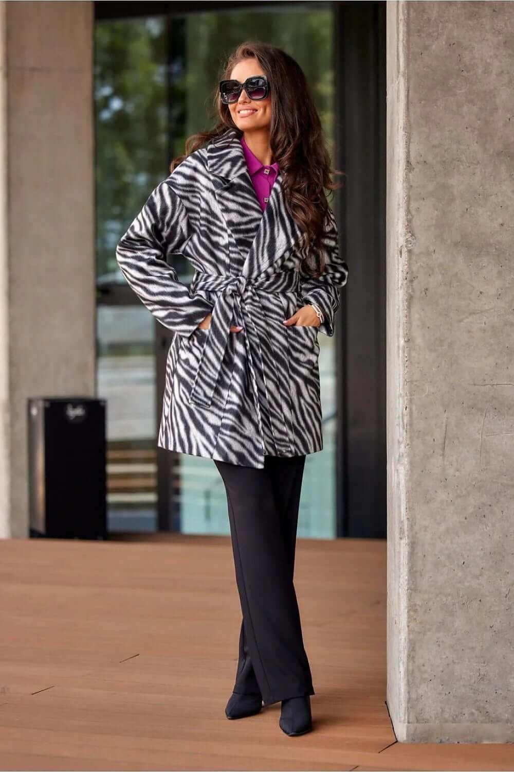 Roco Fashion longline coat with zebra print, belted waist, and large collar, worn stylishly outdoors.