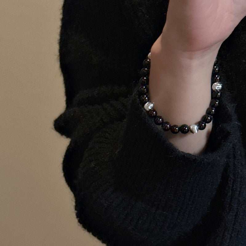 Sterling silver black agate cat's eye bracelet on woman's wrist with black sweater background