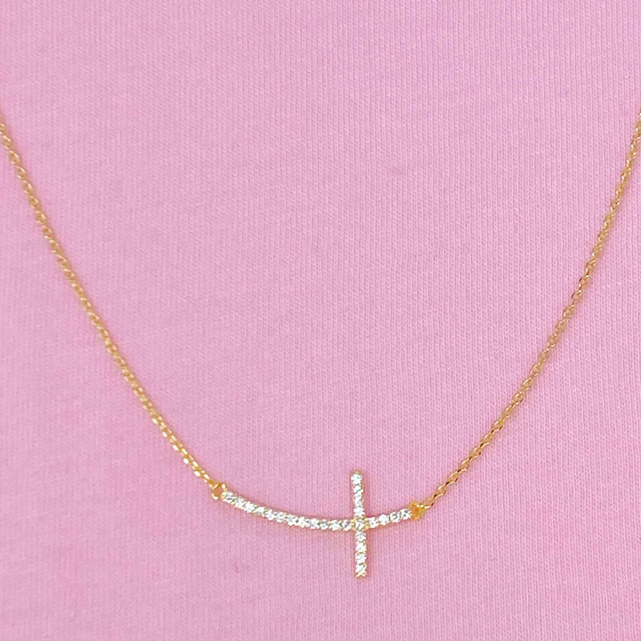 Shiny sideways cross pendant necklace with gold-plated chain, perfect for minimalistic religious style.