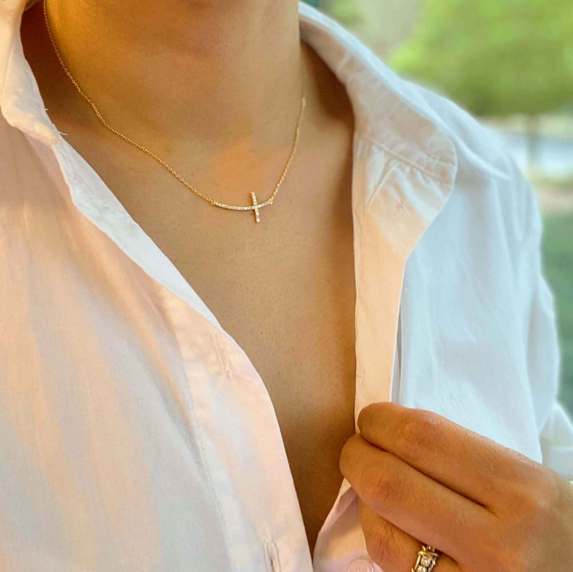 Close-up of a woman wearing a Shiny Sideways Cross Pendant Necklace with gold-plated charm.