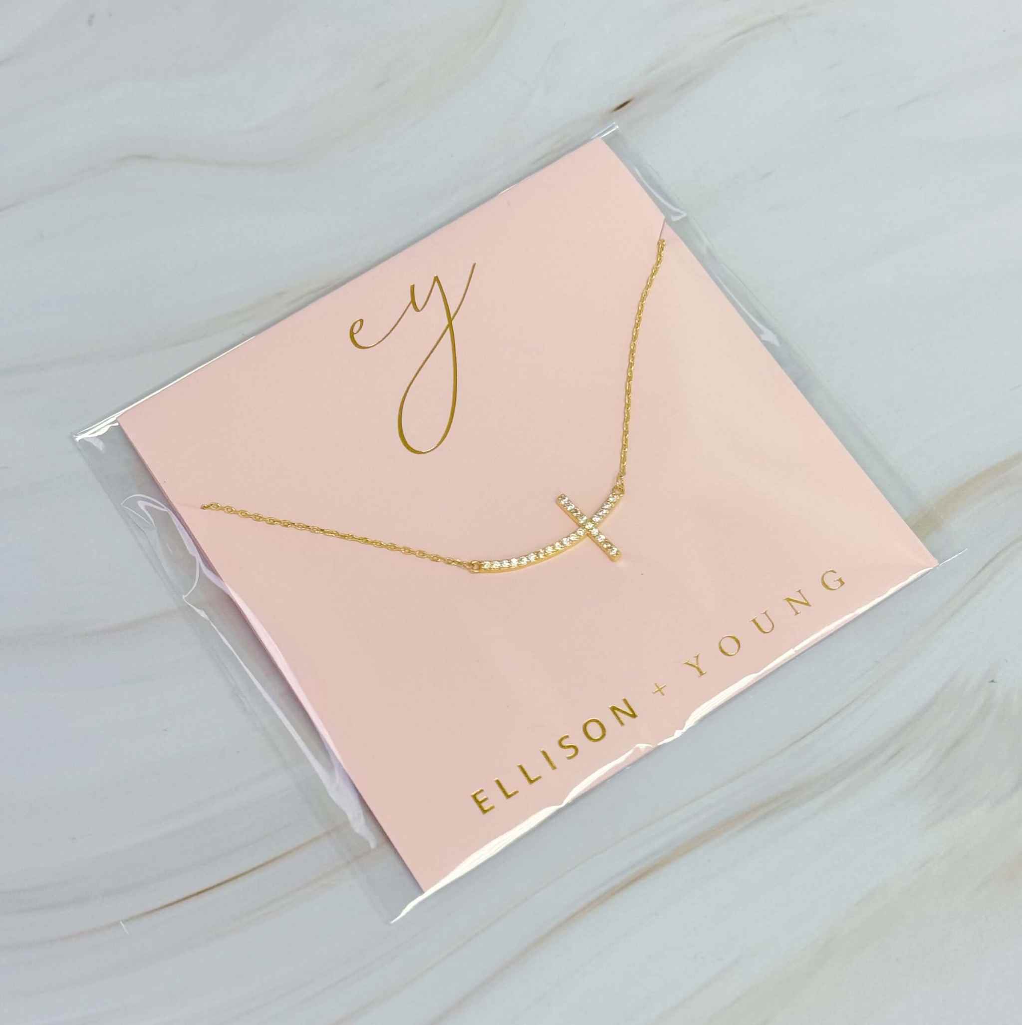 Shiny Sideways Cross Pendant Necklace in packaging by Ellison & Young, featuring a gold-plated design for stylish everyday wear.