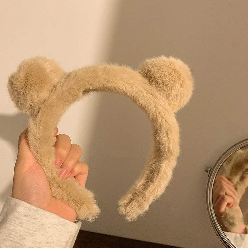 Beige fuzzy Spa Essential Cartoon Hair Tie headband with bear ears held by hand