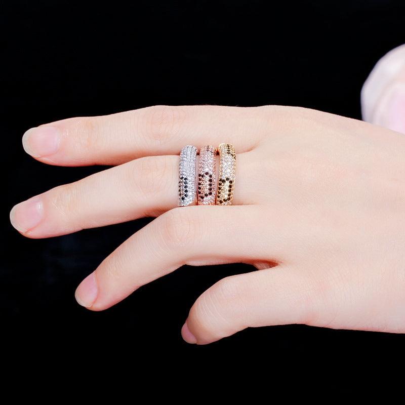 Three sparkling rhinestone zircon fashion rings in platinum, rose gold, and gold on a hand against black background