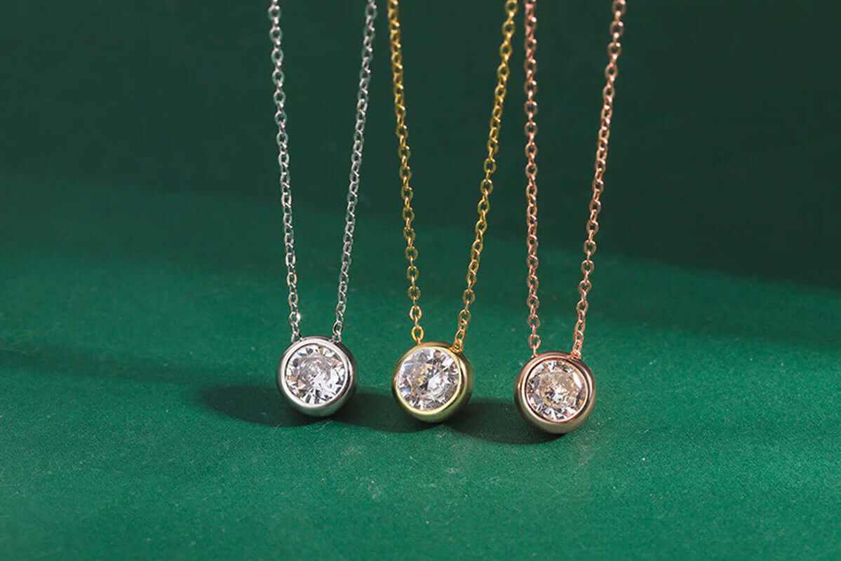 Gold plated zircon choker necklace with round-cut zircon stones in bezel setting on green background