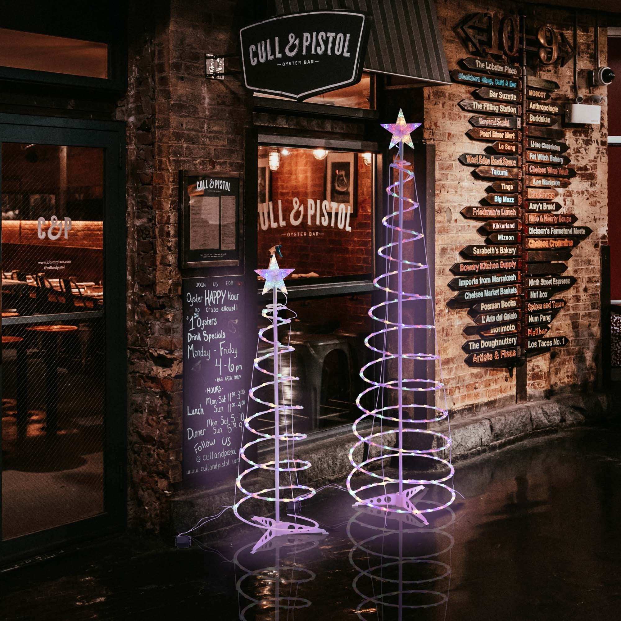 Spiral Christmas tree lights illuminating two spiral tree decorations outside Cull & Pistol restaurant.