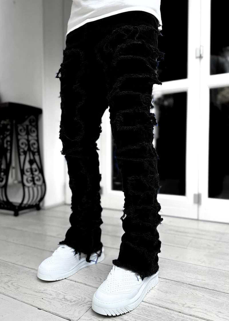 stacked black distressed jeans for men with white sneakers