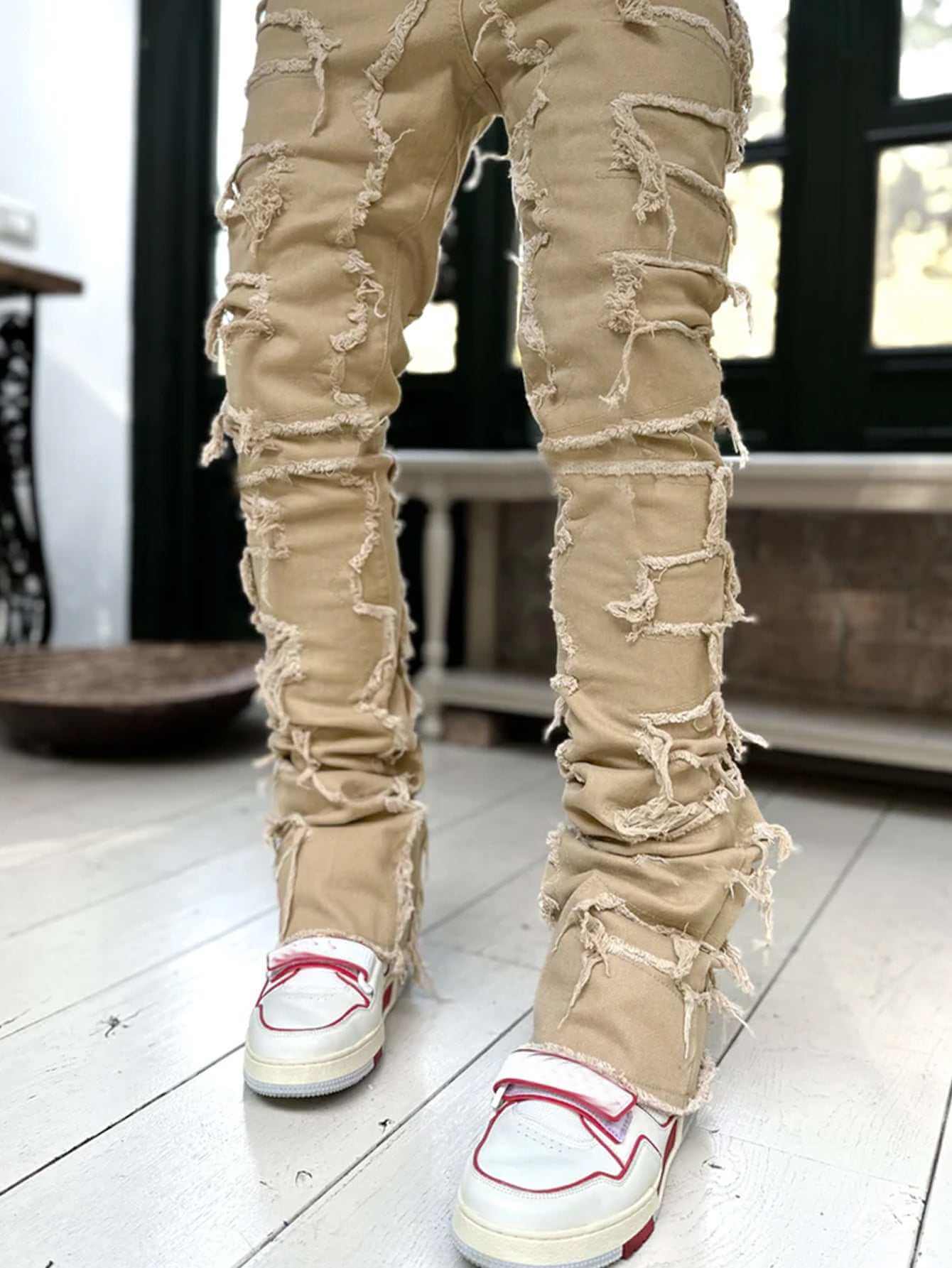 men's beige stacked jeans with distressed design and white sneakers