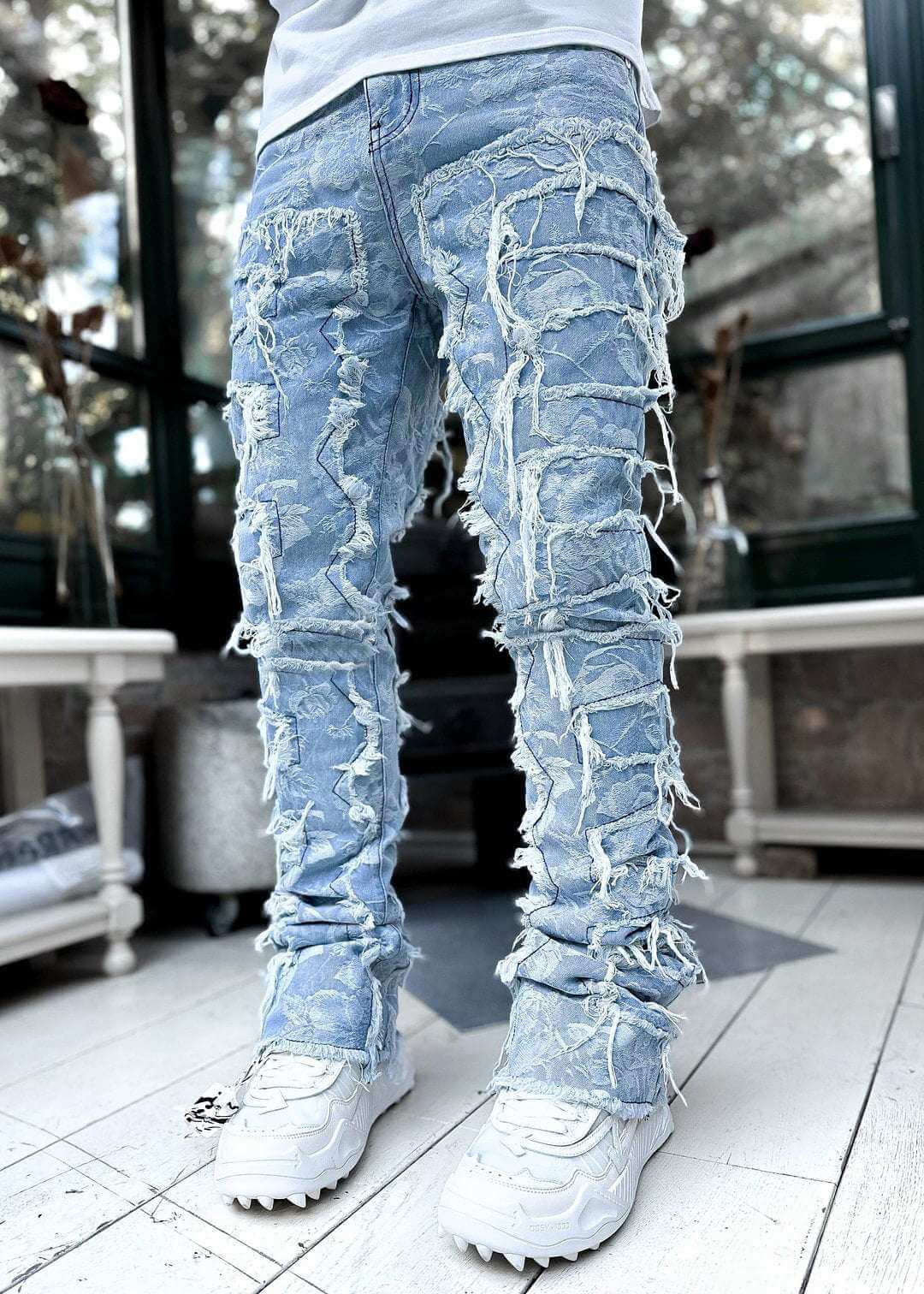 men's light blue distressed stacked jeans with frayed detailing and white sneakers