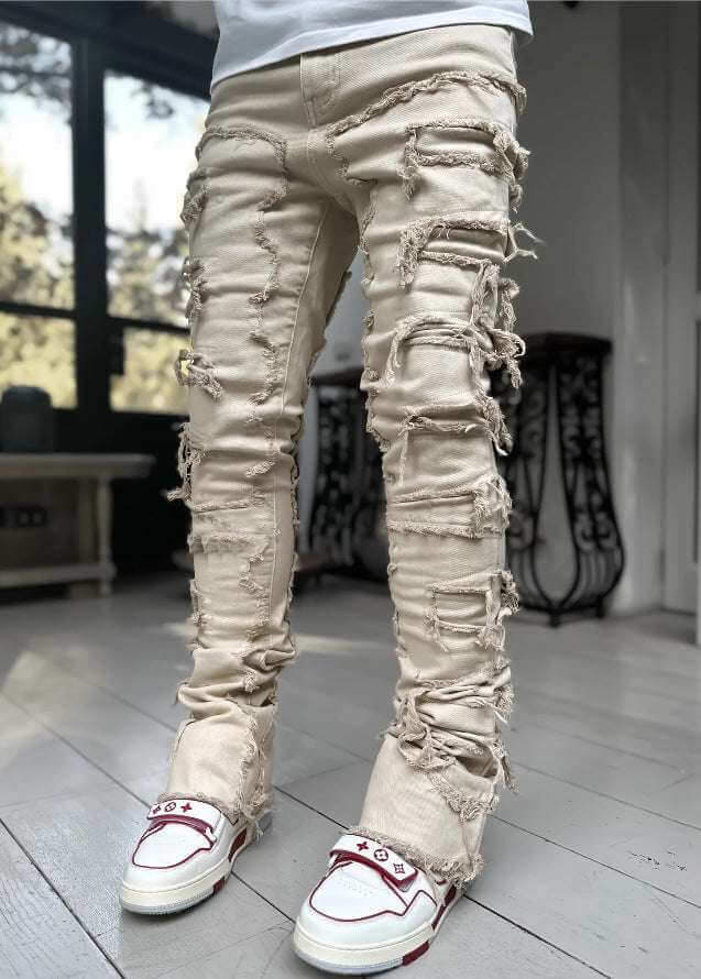 beige stacked jeans for men with distressed design and frayed details in a modern indoor setting