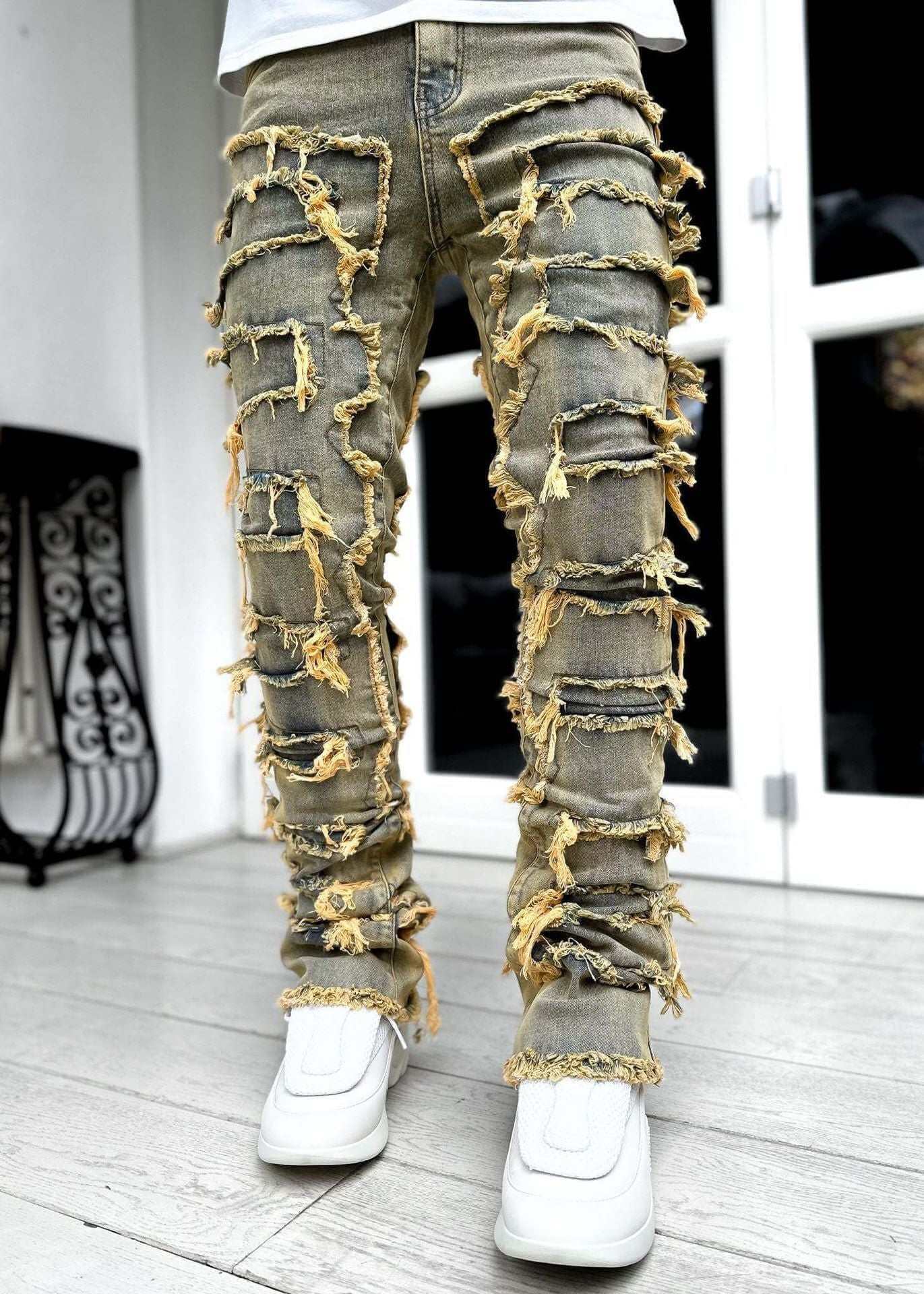 men's stacked distressed jeans with frayed design and white sneakers