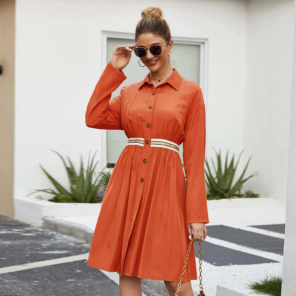 Casual mid-length A-line summer dress for women in orange with lapel collar and elastic waist, accessorized with sunglasses.