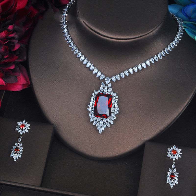 Toast-inspired jewelry set with red gemstone pendant and matching earrings, gold-plated with mixed gem inlay.