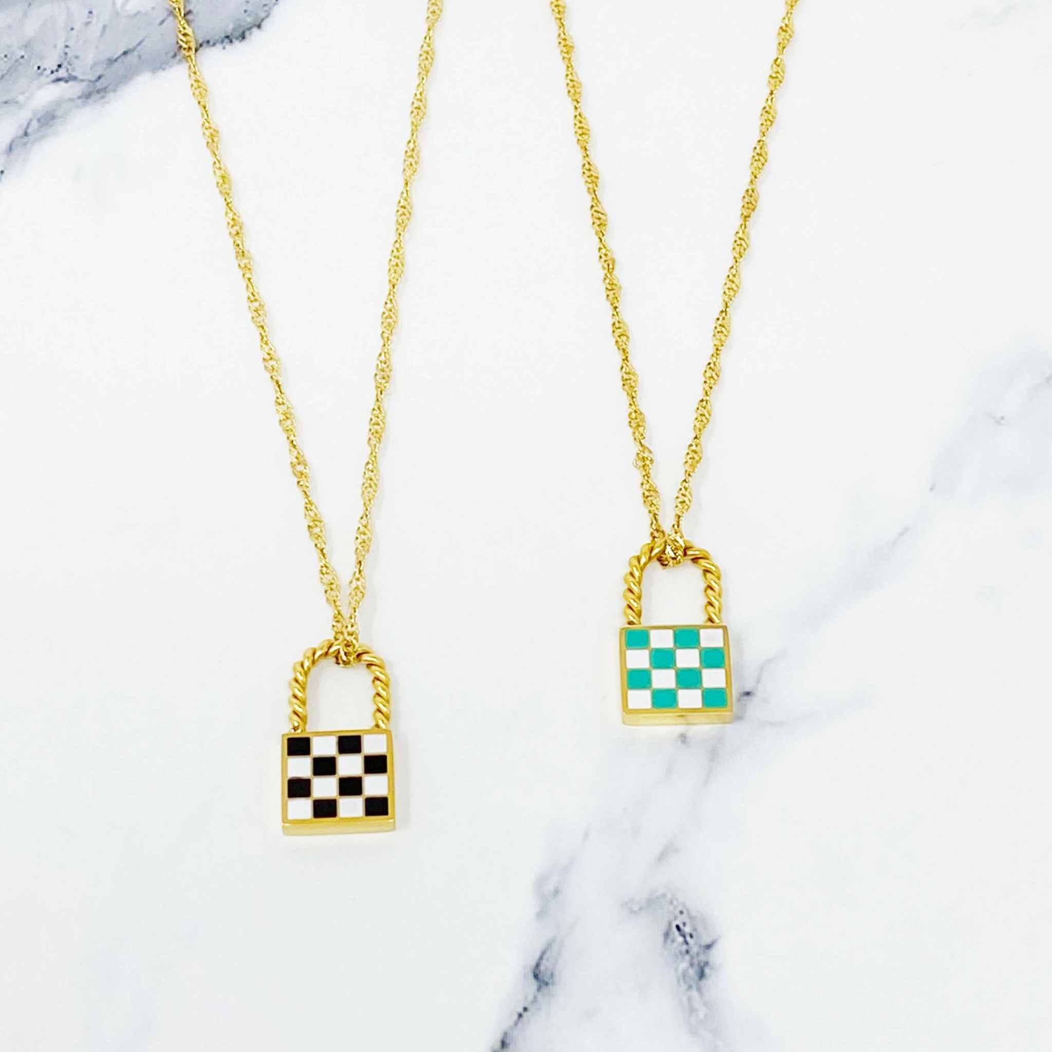 Trendy vintage checkered locket pendant necklaces in gold with black and teal designs on marble background.