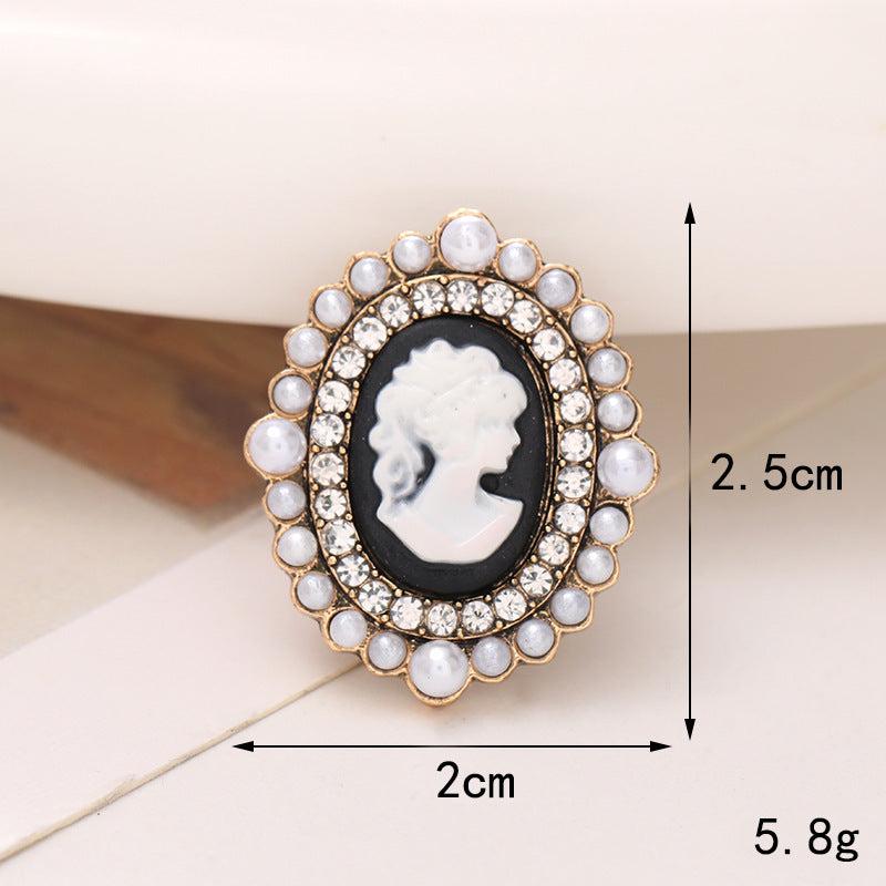 Elegant black and white cameo brooch adorned with pearls and crystals, perfect for accessory styling.