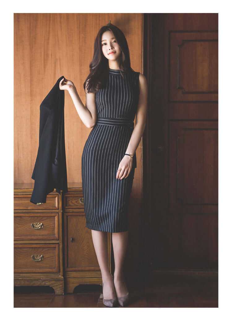 Elegant woman in a fitted black striped dress, holding a blazer, showcasing autumn and spring office style.