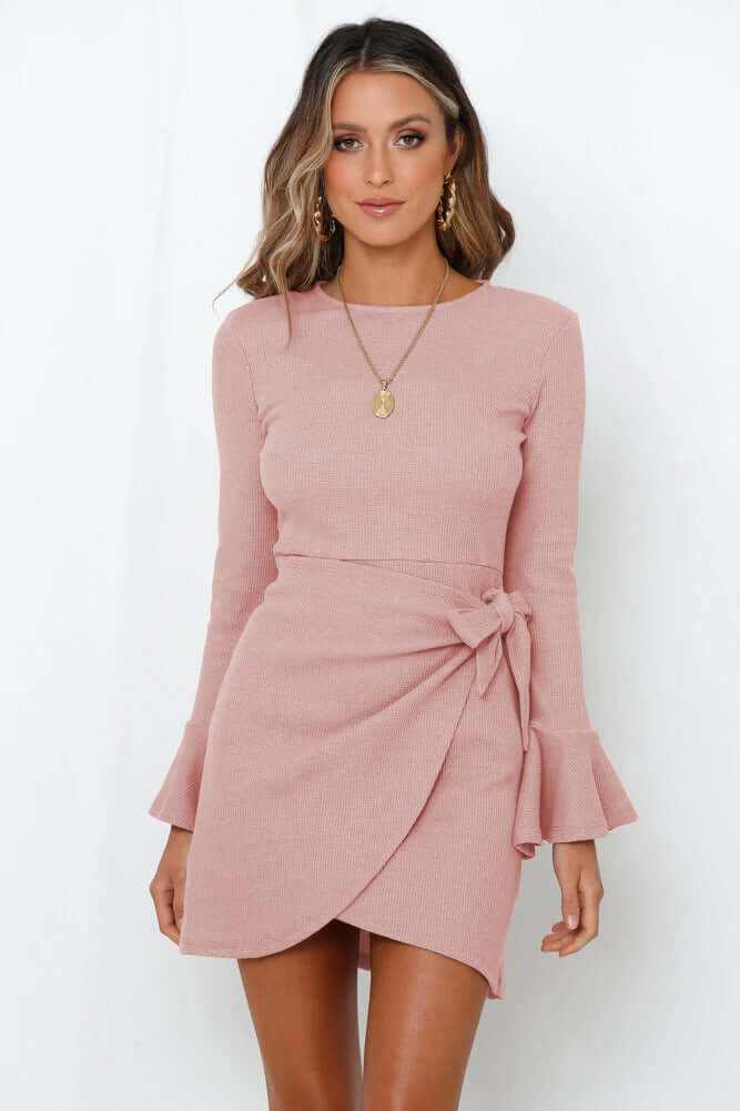 woman wearing pink women's ruffle long sleeve dress with flare sleeves and wrap detail